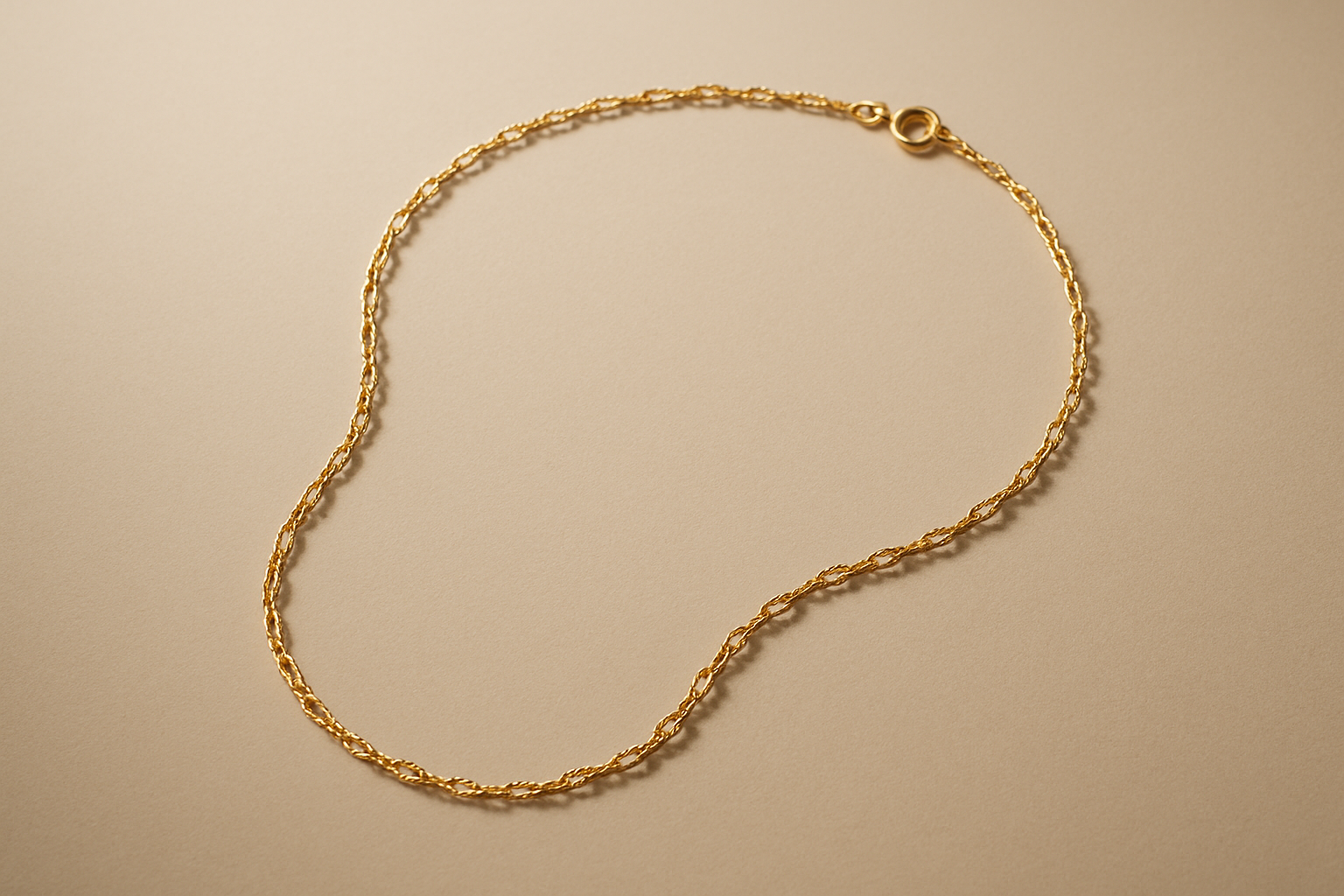 Minimalist product photography of an elegant gold necklace with fine details, placed on a neutral beige background with soft shadows. Luxury aesthetic, clean and modern style, high-resolution studio lighting.